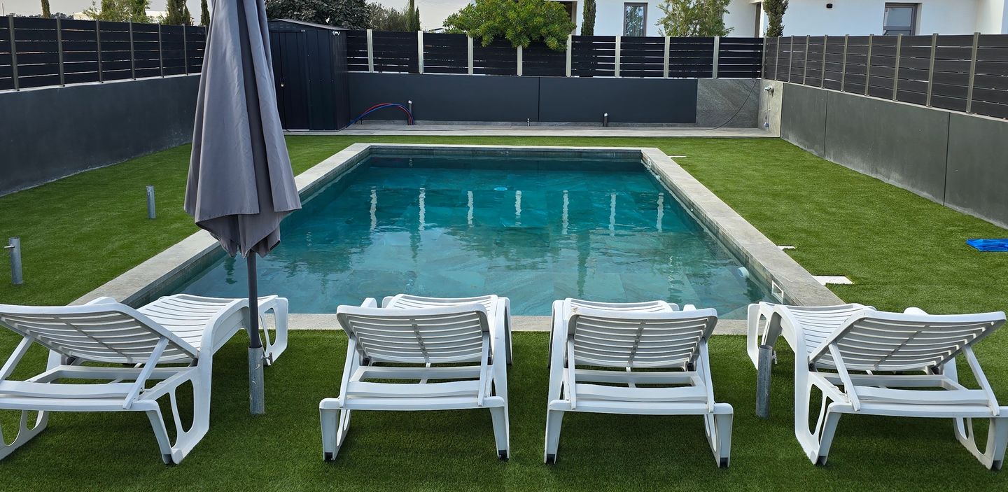 backyard pool with sun loungers on artificial grass in a garden in Cyprus