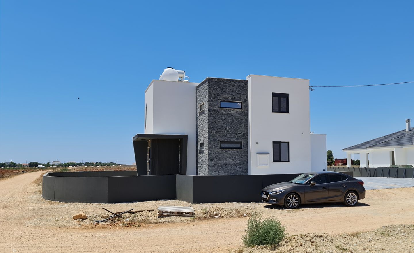 modern white house with photovoltaic panels on the roof and a car