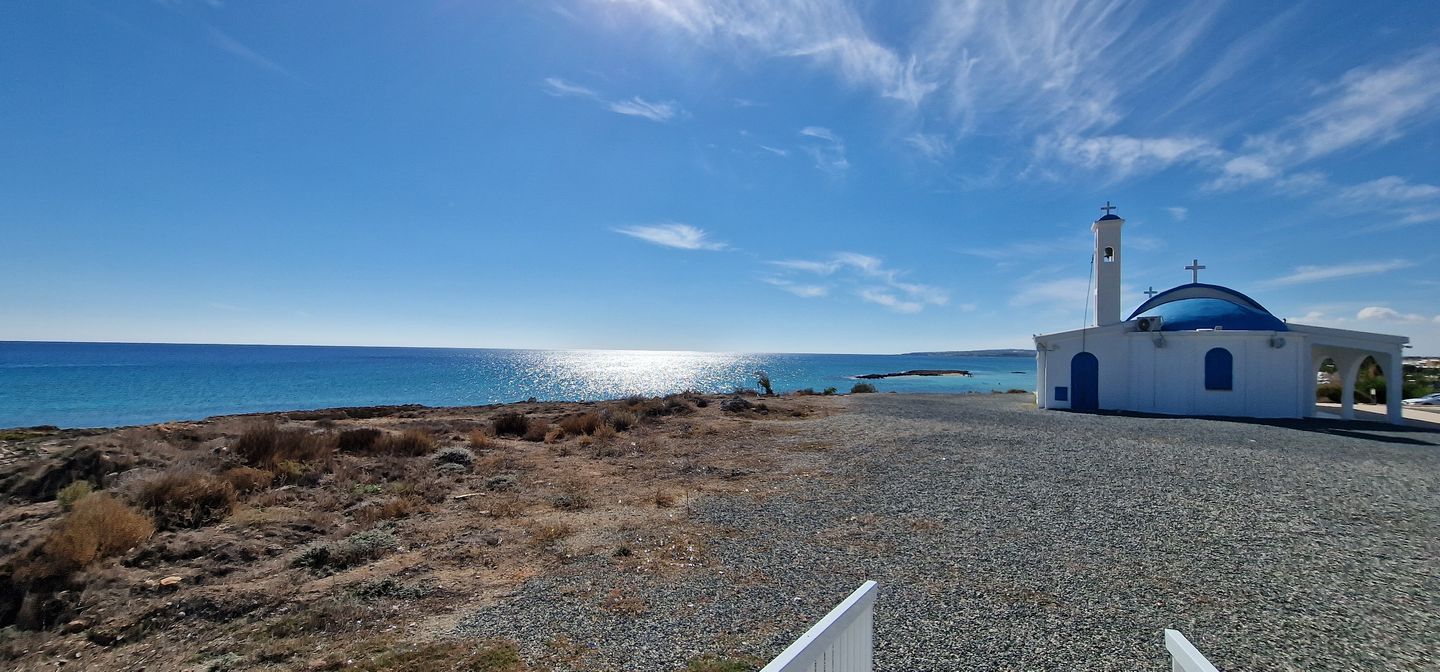 white chapel of Ayia Thekla above a turquoise sea in Cyprus