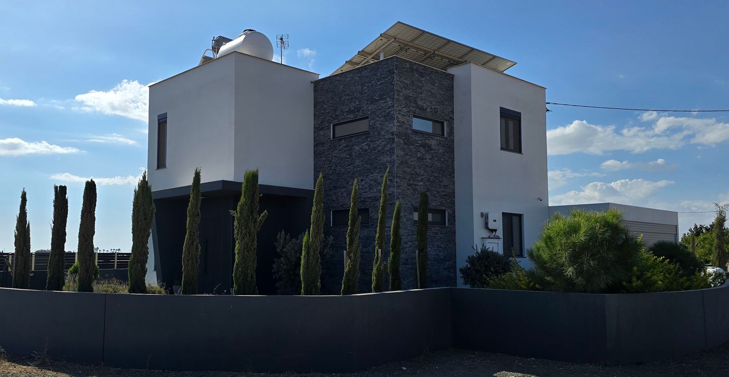 modern white house with stone facade and cypresses in Cyprus