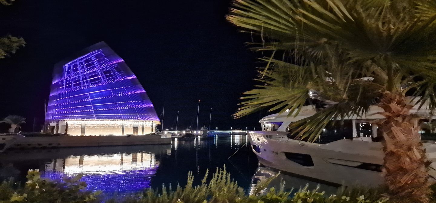 Ayia Napa marina at night with an illuminated building and a yacht